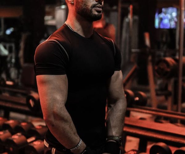 Focused man lifting weights with proper form in a well-lit space.